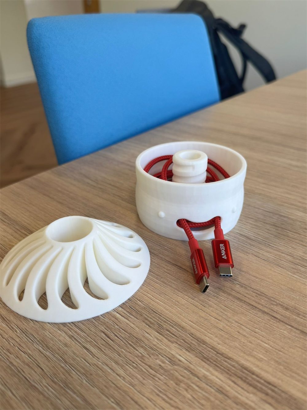 The printed desk tidy open on a desk, a red cable wound around the central column inside the body