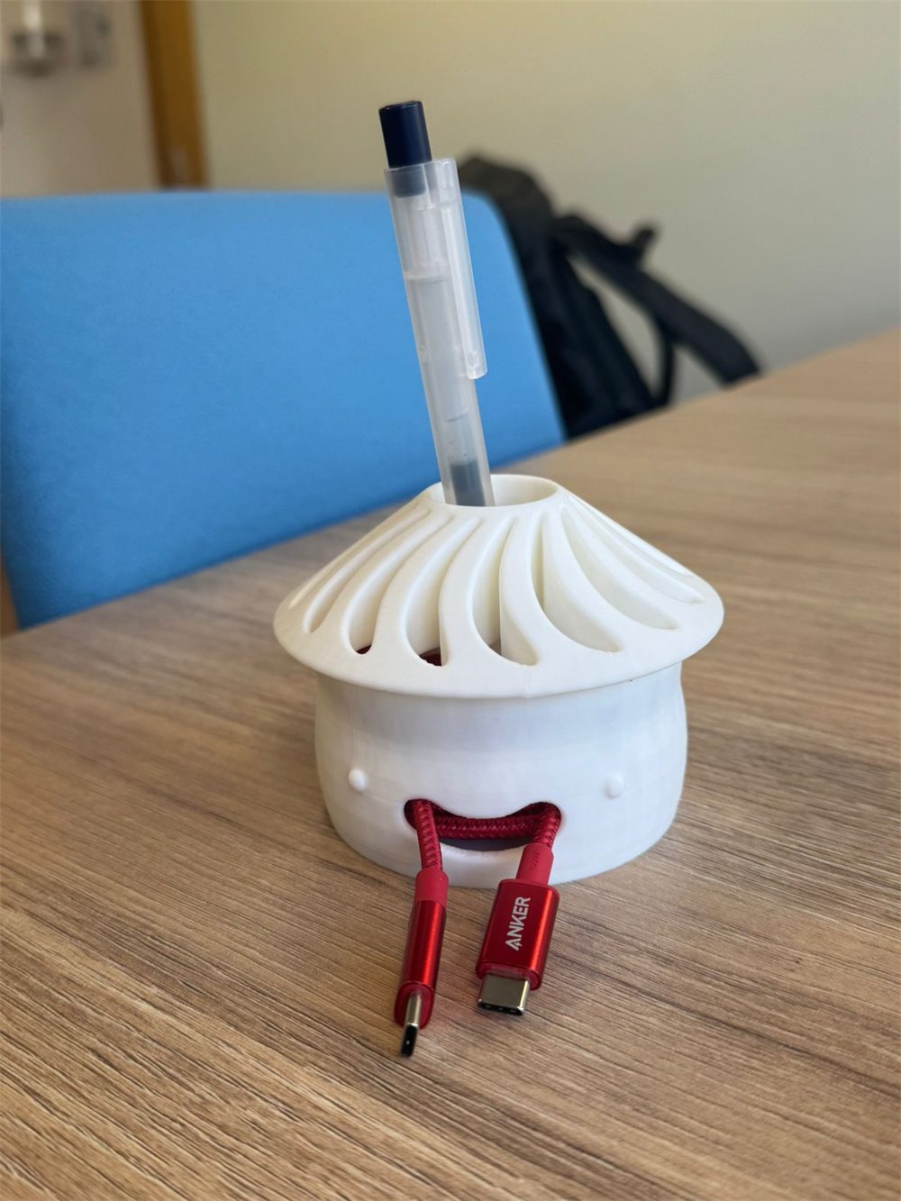 The desk tidy closed, a pen standing in the hole at the top of the hat and the cable ends coming out of the mouth