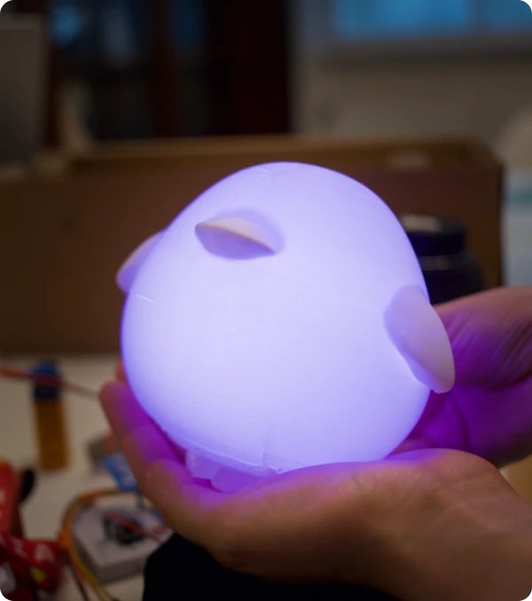 The duck prototype held in one hand, glowing purple, showing how small it is